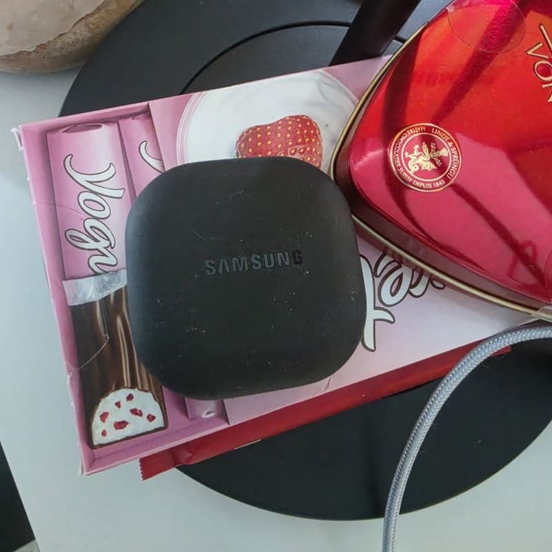 Original photo of a Samsung earbuds case on a cluttered background